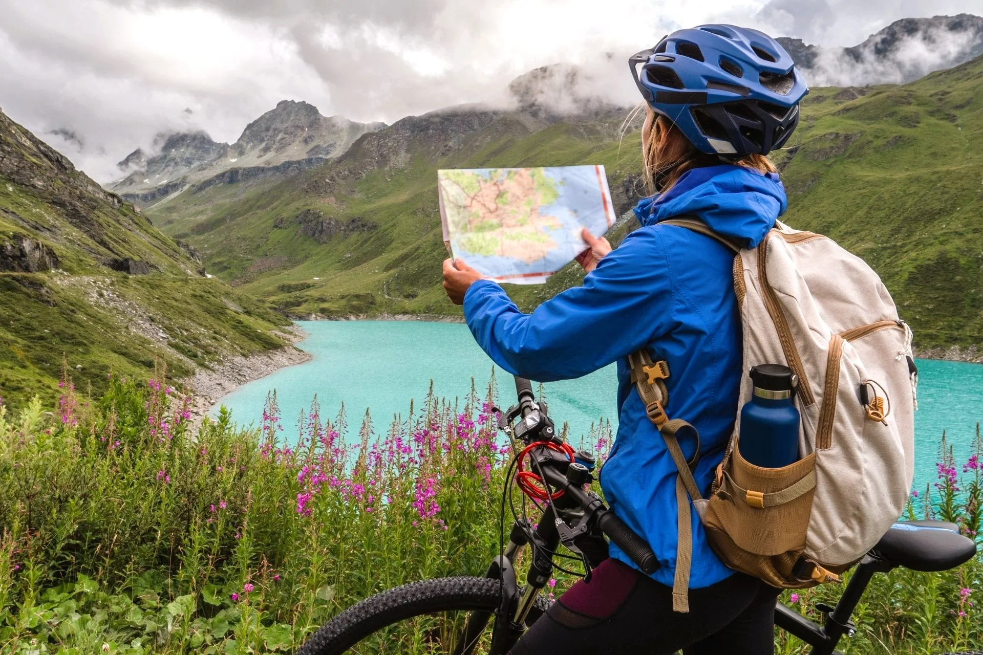Female cyclist near an alpine lake looking at a map.