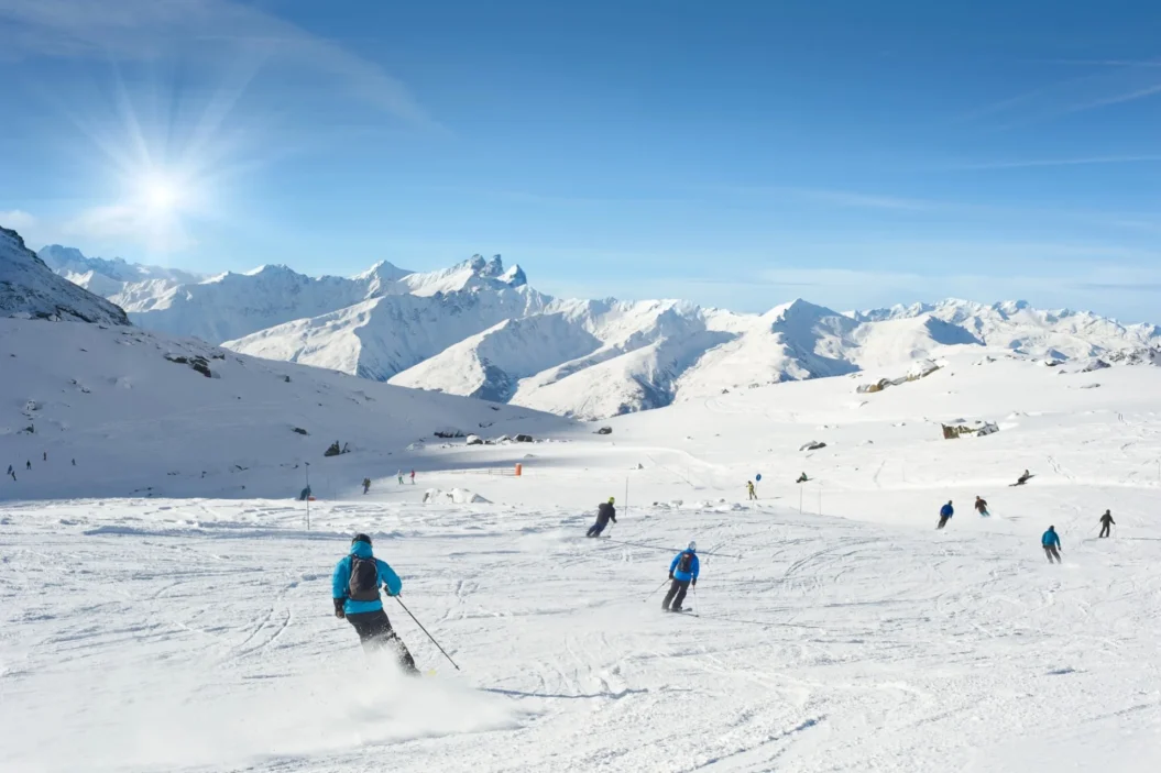 Skiers on wide open slope in high mountains.